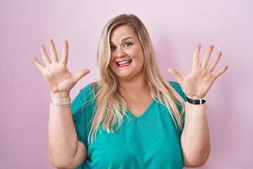 Wall Mural - Caucasian plus size woman standing over pink background showing and pointing up with fingers number ten while smiling confident and happy.