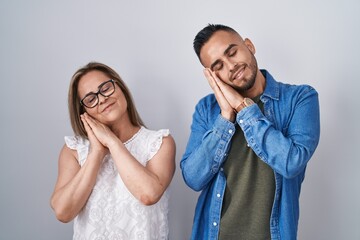 Canvas Print - Hispanic mother and son standing together sleeping tired dreaming and posing with hands together while smiling with closed eyes.