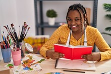 African American Woman Artist Smiling Confident Reading Book At Art Studio