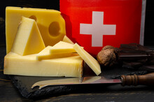 Assortment Of Swiss Cheeses Emmental Or Emmentaler Medium-hard Cheese With Round Holes, Gruyere, Appenzeller Used For Traditional Cheese Fondue And Gratin And Flag Of Switzerland