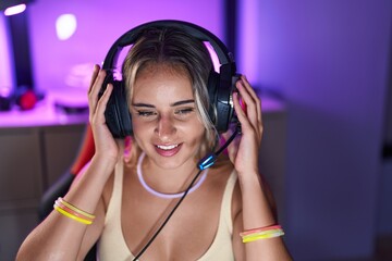 Wall Mural - Young blonde woman streamer smiling confident sitting on table at gaming room