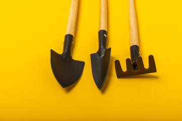 Wall Mural - Garden tools on a yellow background, top view. Garden shovels and rakes. Concept of gardening, landscaping and hobby. Place for text.