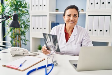 Sticker - Middle age hispanic woman wearing doctor uniform holding xray at clinic