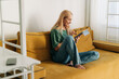 © Ilona - Attractive blond woman works using an electronic tablet while sitting on the sofa at home.