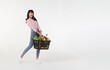 © NaMong Productions - Happy Asian woman holding shopping basket full of vegetables and groceries, studio shot isolated on white background. copy space