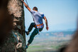 © qunica.com - Young male climber hanging by a cliff