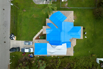 Poster - Top view of leaking house roof covered with protective tarp sheets against rain water leaks until replacement of asphalt shingles. Damage of building rooftop as aftermath of hurricane Ian in Florida