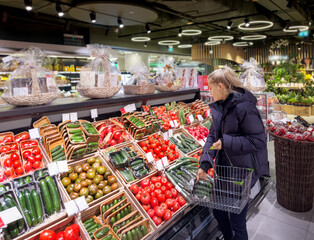 Wall Mural - Woman buying vegetables(tomatoes and cucumbers) at the market