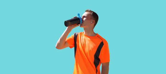 Portrait of tired runner man drinking from bottle the water or protein shake, male sportsman resting after hard training isolated on blue background