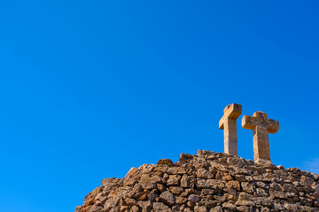 A cross dug into a stone on a mountain against a blue sky