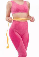 Wall Mural - Fitness woman with a fit figure with her hands behind her head shows her figure and body.Fit woman in pink sportswear isolated on a white background showing her figure and smiling.In a pink outfit
