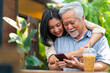© CandyRetriever  - Happy Asian woman teaching elderly father using mobile phone application during having lunch together at restaurant on summer vacation. Family relationship older people mental health care concept.