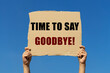 Time to say goodbye text on box paper held by 2 hands with isolated blue sky background. This message board can be used as business concept to say to others it is time to say goodbye.