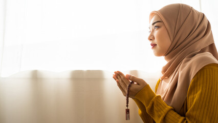 Beautiful Asian Muslim woman in hijab dress sitting in mosque and praying. People reading Quran .