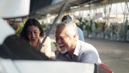 Wall Mural - 4K Asian couple with elderly father put potted plants and flower in car trunk together after buying plant at street market on summer vacation. Family relationship and senior people mental health care.