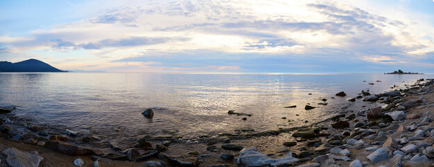 Wall Mural - Sunset over the lake Baikal on a sunny summer day. Pebble beach. Panorama, banner.