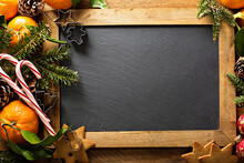 Christmas Background With Chalkboard, Pine Branches And Oranges