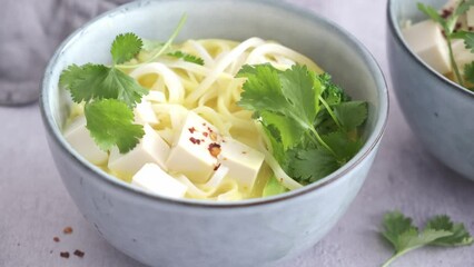 Wall Mural - Vegan laksa with rice noodles, broccoli and tofu in blue bowls, gray background.