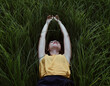 © Cavan Images - Young woman lying down on a green grass.