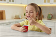 Cute little girl enjoying tasty yogurt at white marble table in kitchen