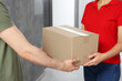 © New Africa - Courier giving parcel to customer in hallway, closeup