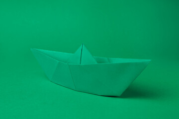 Sticker - Origami art. Paper boat on green background