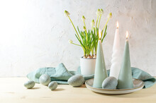 Easter Eggs And Candles In Pastel Turquoise Color And A Potted White Grape Hyacinth On A Wooden Table Against A Light Plastered Wall, Holiday Decoration, Greeting Card, Copy Space
