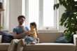 Cheerful playful dad tickling excited girl on couch, cuddling kid on home sofa, enjoying fatherhood, playtime with little daughter. Father and child playing active funny game, laughing