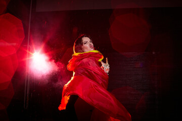 Witch woman in red cloak with skull on black background and light in night. Female warrior in the Dark