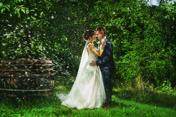 Sticker - a bride and groom is dancing happily in garden under water drops