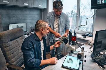 Two men work in an office with the production and development of microcircuits.Concept of engineering, chip development and service.