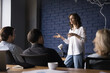 canvas print picture - Engaged confident business project female leader talking to team, telling strategy, plan, presenting tasks. Serious pretty presenter girl speaking to coworkers, brainstorming on meeting
