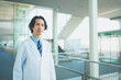 © HML - 白衣を着て病院の廊下を歩く若い男性医師