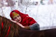 Russian beauty girl in traditional clothes lying on the back of a red big horse in forest winter
