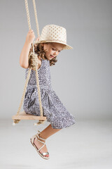 happy little girl swinging on a wooden swing