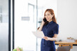 © David - Cheerful business Asian woman freelancer making telephone call share good news about project working in office workplace, business finance concept.