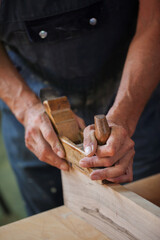 Carpenter using working tools while working on a wood in carpentry workshop