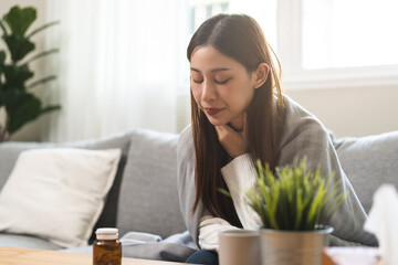 Wall Mural - Sick, hurt or pain asian young woman, girl with sore throat, cough have a fever, flu and sneezing nose, runny sitting on sofa bed at home. Health care person on virus seasonal.