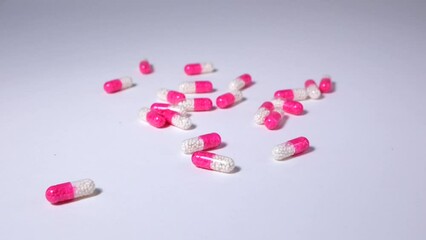 Wall Mural - Group of the same pink medical pills, falls on white backgrounds, close up. Health care and medicine. Healthy lifestyle. Slowmotion.