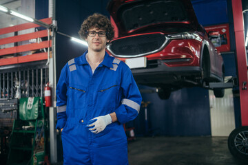 Wall Mural - Car mechanic or engineer standing and looking at camera at auto repair shop.