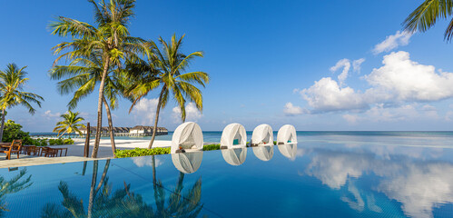 Stunning landscape, swimming pool blue sky with clouds. Tropical resort hotel in Maldives. Fantastic relax and peaceful vibes, chairs, loungers under umbrella and palm leaves. Luxury travel vacation
