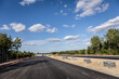Budowa nowej autostrady. Montaż barier ochronnych i znaków przy nowo budowanej autostradzie. Nowy asfalt.