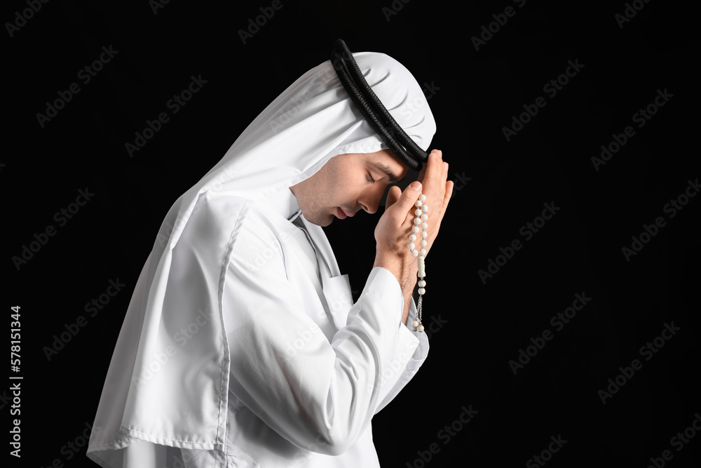 Praying Muslim man on dark background