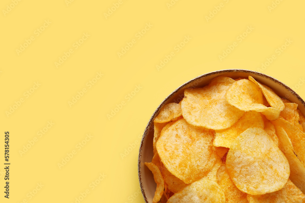 Bowl with delicious potato chips on yellow background