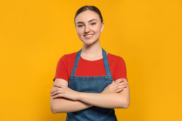 Wall Mural - Beautiful young woman in clean denim apron on orange background