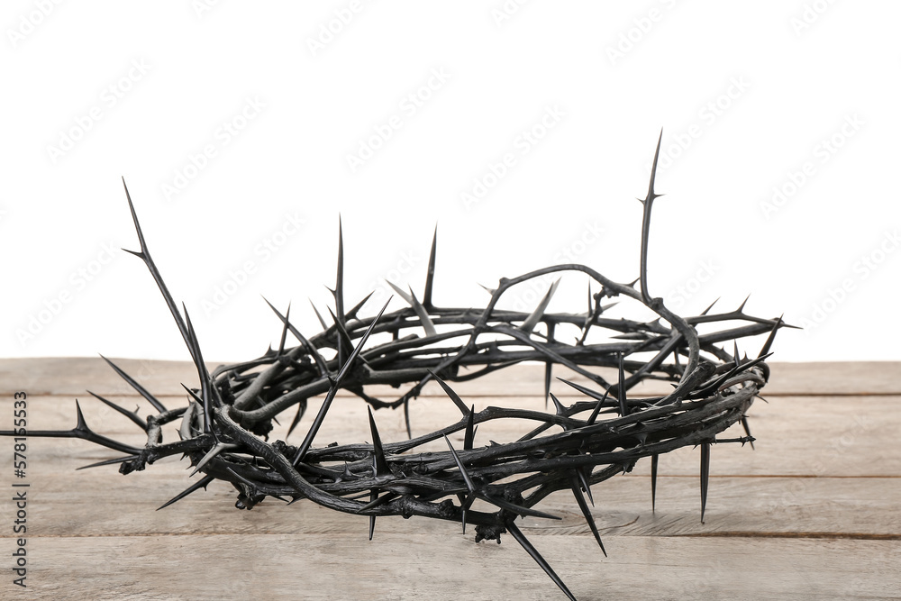 Crown of thorns on wooden table against white background