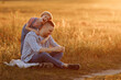 © Kaplitskaya Love - A heartwarming moment captured in time as a little girl in denim overalls embraces her father from behind while they enjoy a summer evening walk in the fields.