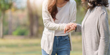 Close Up Of Adult Daughter Holding Her Elderly Mother Hand With Love And Walk Together