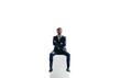 Confident young businessman sitting on top of a block on a transparent background