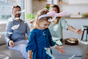 Wall Mural - Little girl with bunny ears celebrating Easter with her parents.